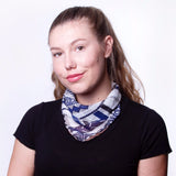 A model wearing a chiffon navy pattern face mask as a scarf around her neck.