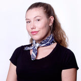 A model wearing a chiffon navy pattern face mask as a scarf around her neck. 