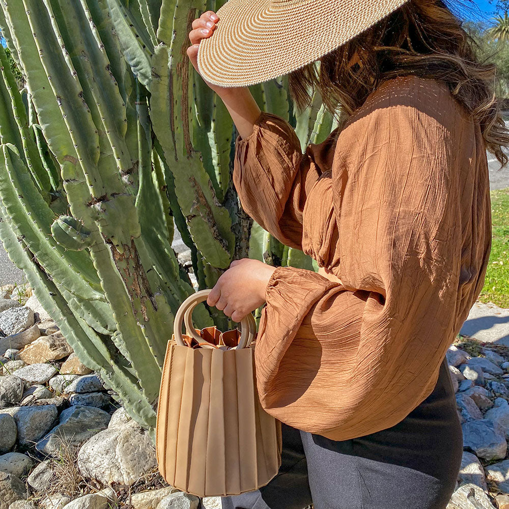 A model wearing a woven top and shrug set with a cactus in the background. 