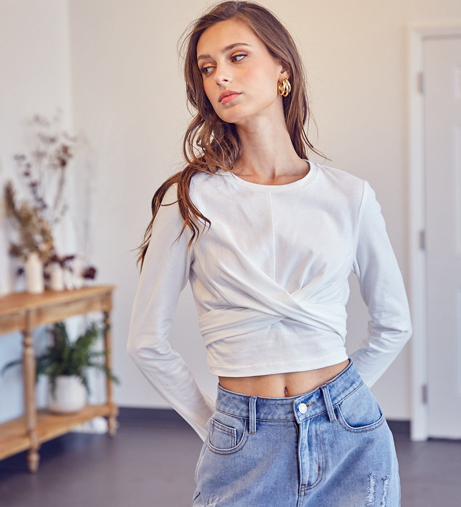 A model wearing a white front cross back tie top against a white wall. 