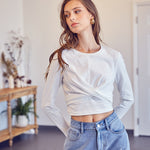 A model wearing a white front cross back tie top against a white wall. 