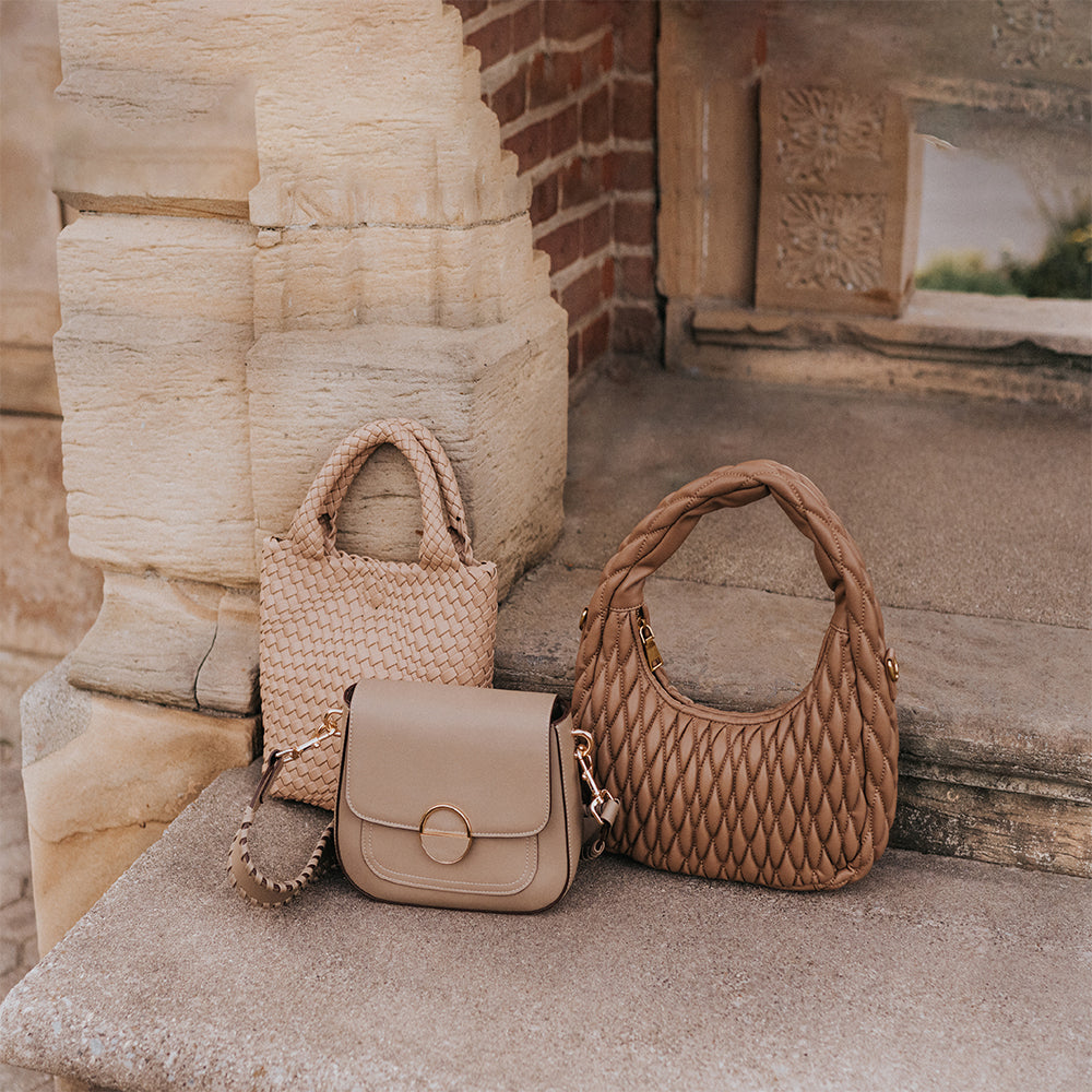 A still image of three vegan leather handbags sitting on a concrete stair. 