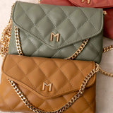 A still image of three small quilted vegan leather shoulder bags laying against each other.