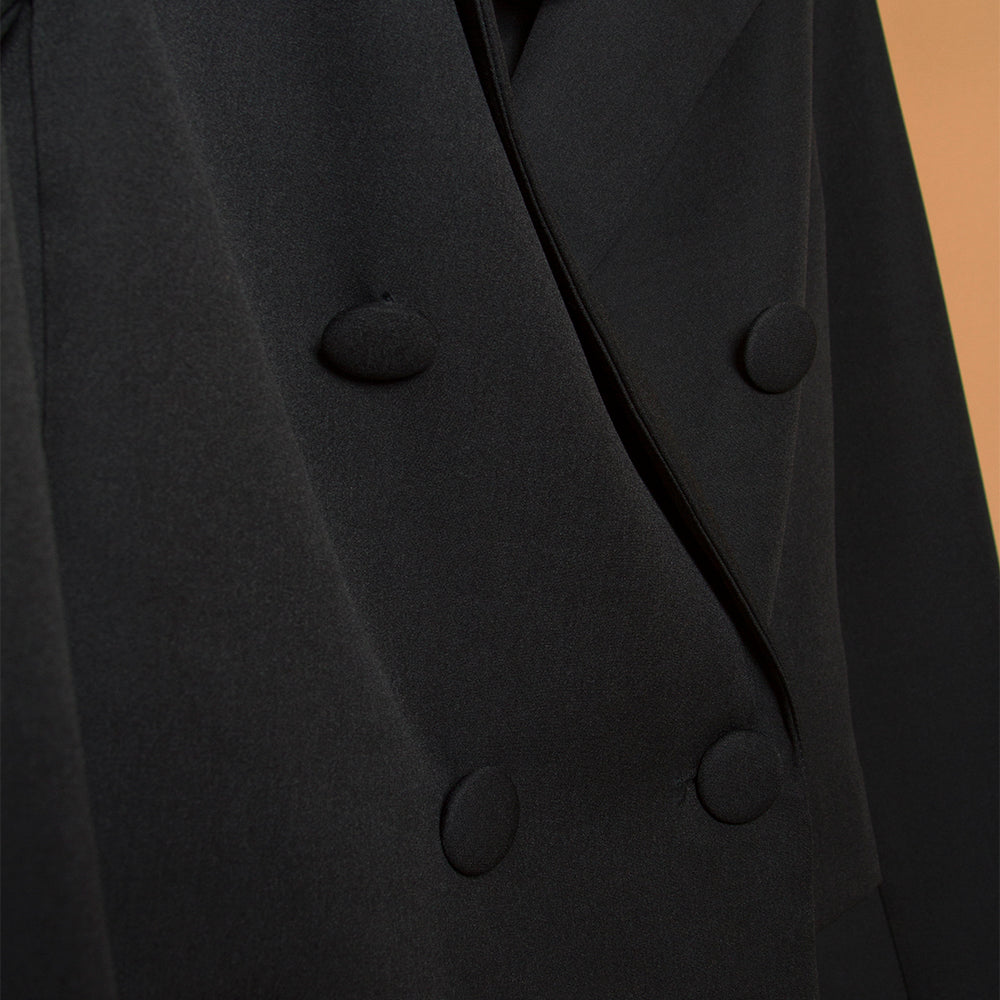 A detail image of a black double breasted cropped jacket.