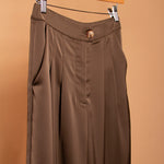 A detail image of tan satin straight leg pant on a hanger. 