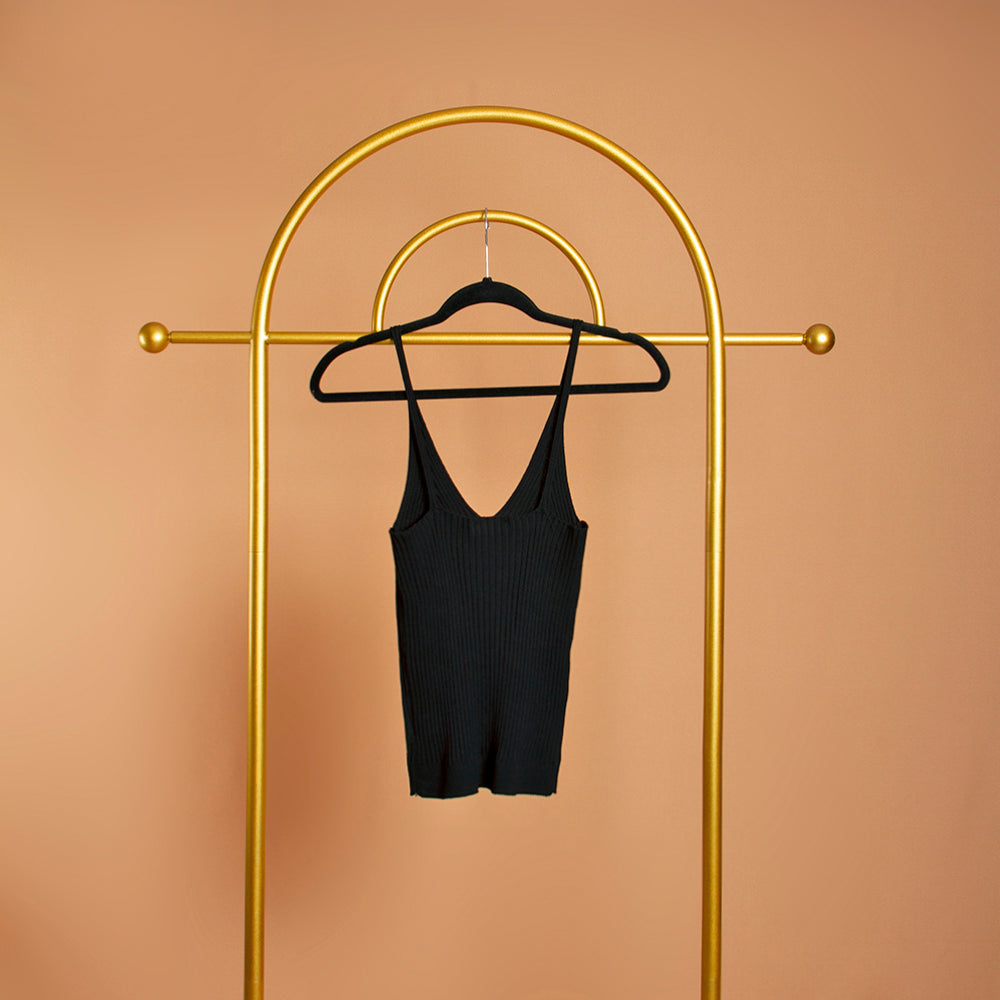 A black rib-knit tank top on a hanger against an orange background. Backside view. 