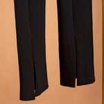 A detailed image of black front slit high waist leggings against an orange background. 