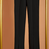 A detailed image of black front slit high waist leggings on a hanger against an orange background. 