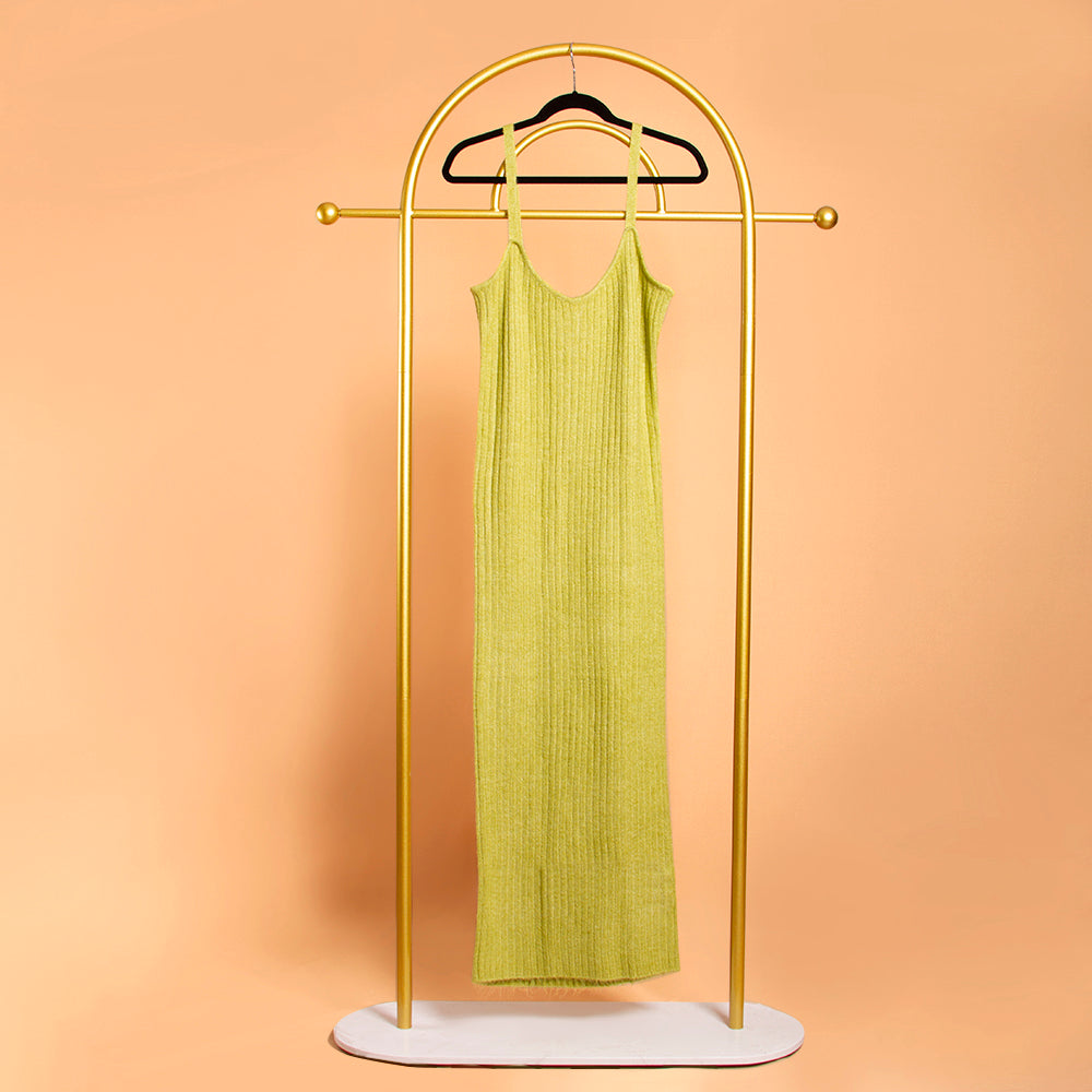 A still image of a green midi rib knit dress on a hanger with a orange background.