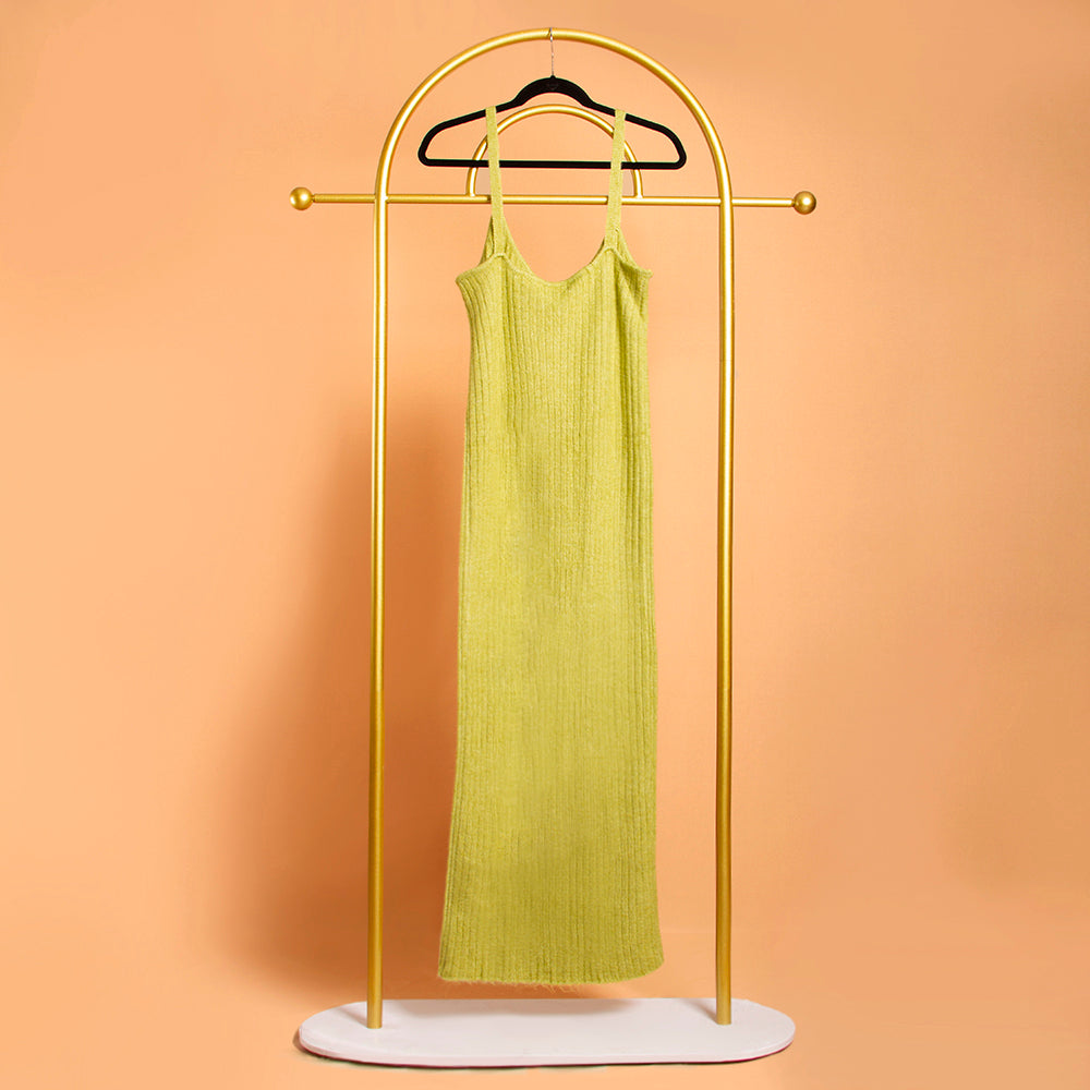 A still image of a green rib knit midi dress backside view on a hanger with an orange background. 