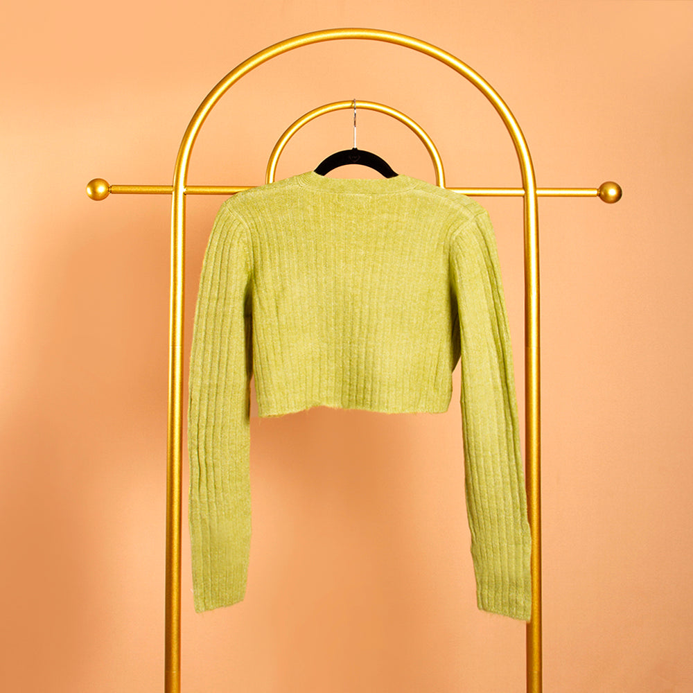 A still image of a green rib knit cardigan from the backside view on a hanger against an orange background. 