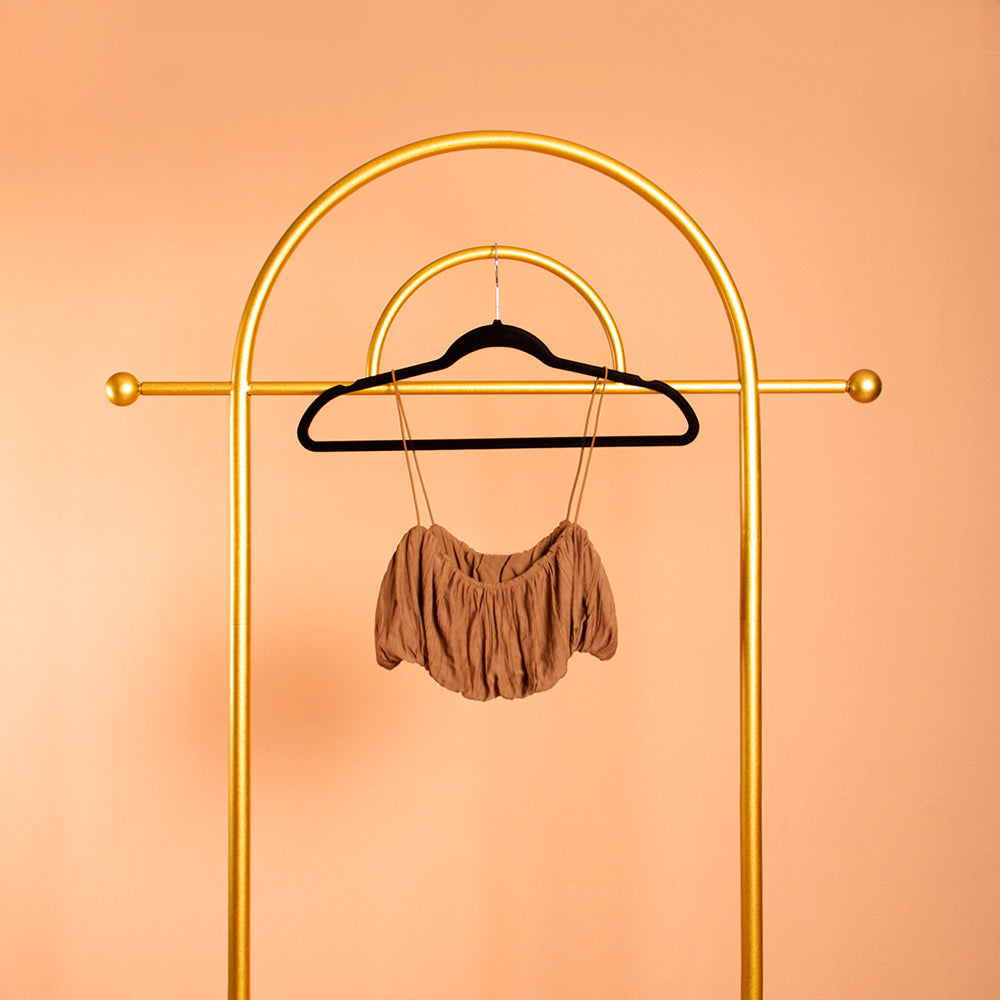 A still image of a woven crop top on a hanger against an orange wall. 