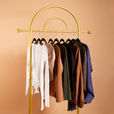 A still image of multiple clothing items on hangers against an orange background. 
