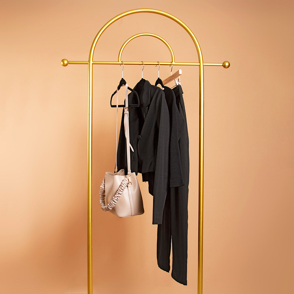 A still image of an outfit with a black jacket, black top, and black pant, with a vegan leather handbag on hangers. 