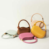 A still image of five structured vegan leather crossbody bags with marble pearl accessory against a white wall. 
