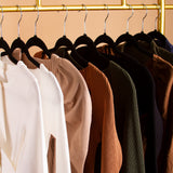 A still image of multiple clothing tops hanging together on a rack. 