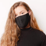 A model wearing a black solid face mask with adjustable strings on each side. 