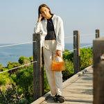 A model wearing a small crystal beaded top handle bag while outside on a wooden bridge. 