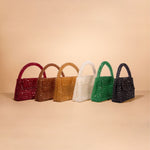 A still image of six different crystal beaded top handle bag against a tan wall. 