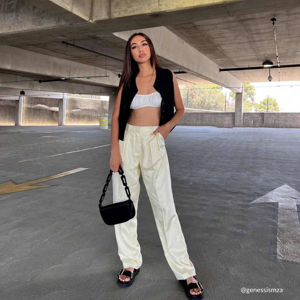 A model wearing a black recycled vegan leather shoulder bag outside in a parking garage. 