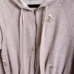 A detail image of a grey terry hooded romper with flower details. 