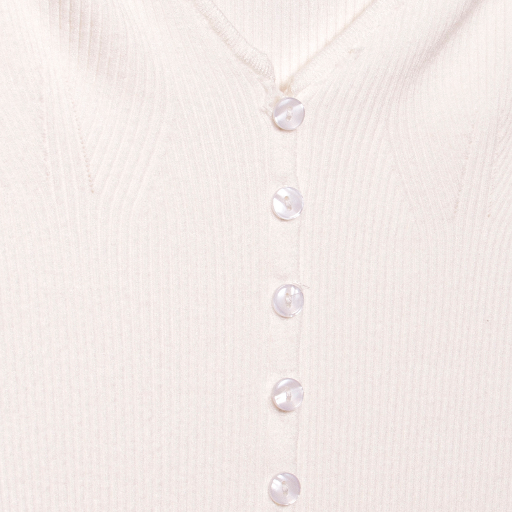 A detail image of a white long sleeve rib knit cardigan with buttons. 