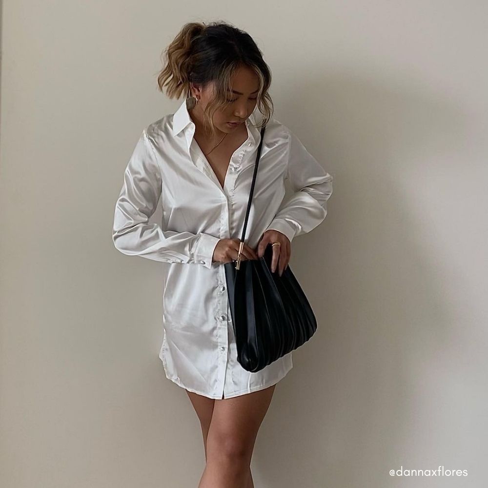 Model wearing a black pleated vegan leather shoulder bag. 