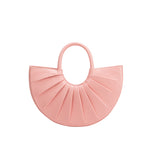 A small pink semi circle vegan leather top handle bag with pleated details.