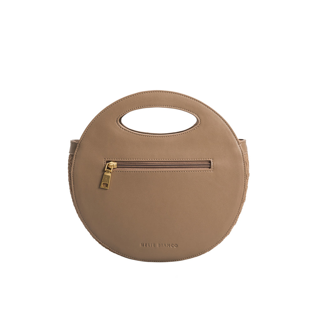 A taupe circle shaped vegan leather crossbody bag with woven pattern.