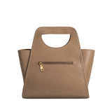 A taupe square shaped recycled vegan leather top handle bag. 