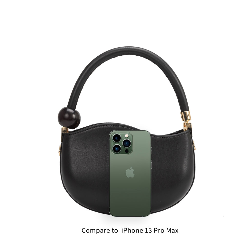 An iphone 13 pro size comparison image for a small structured vegan leather crossbody bag with a marble pearl accessory.
