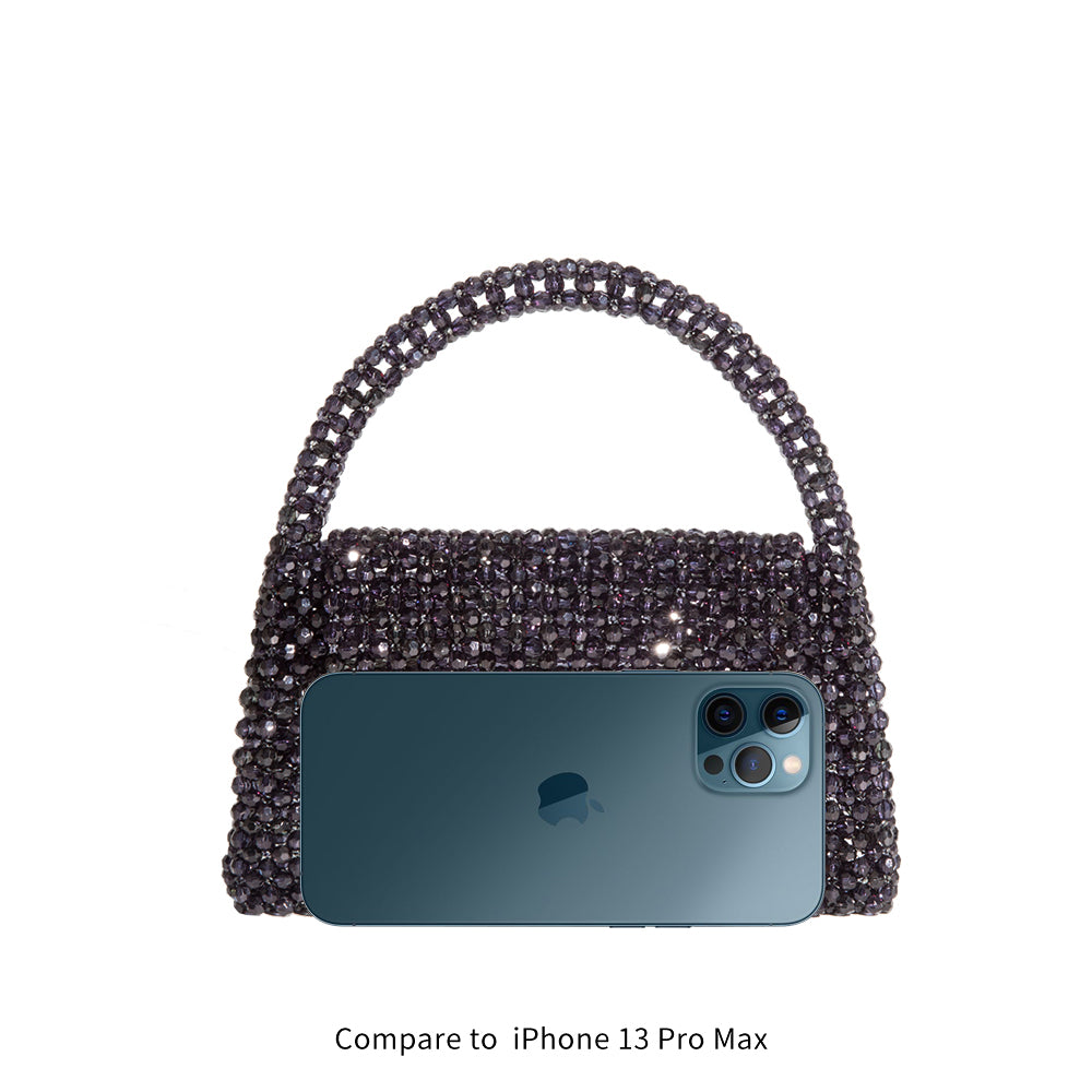 An iphone 13 pro size comparison image for a small beaded top handle bag with a flap closure. 