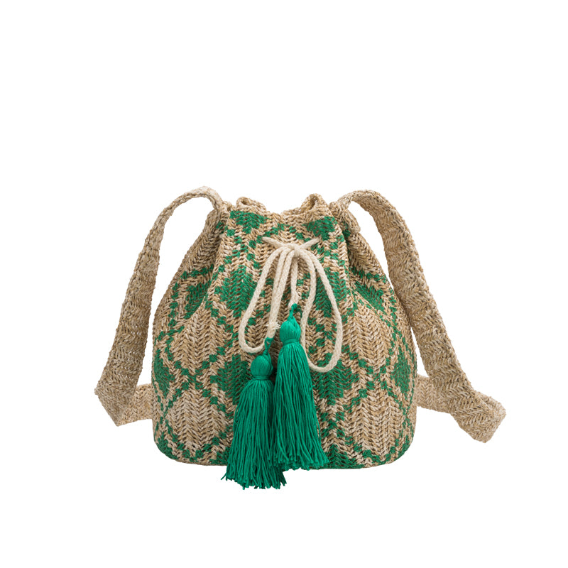 A small green straw drawstring crossbody bag with green pompoms.