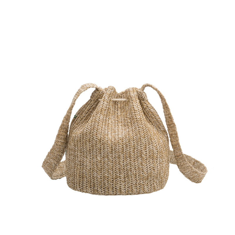 A small green straw drawstring crossbody bag with green pompoms.