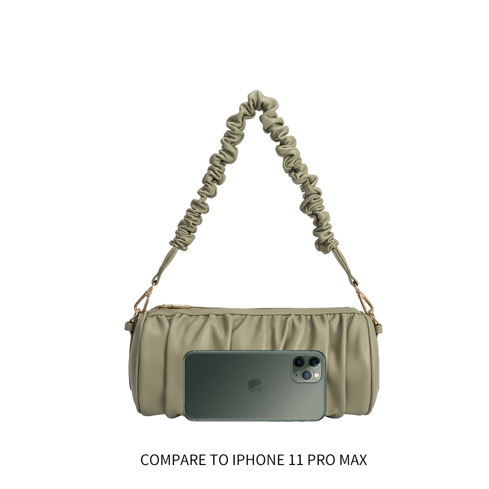 An iphone 11 pro size comparison image for a medium moss cylindrical-shaped shoulder bag with a ruched body and strap. 