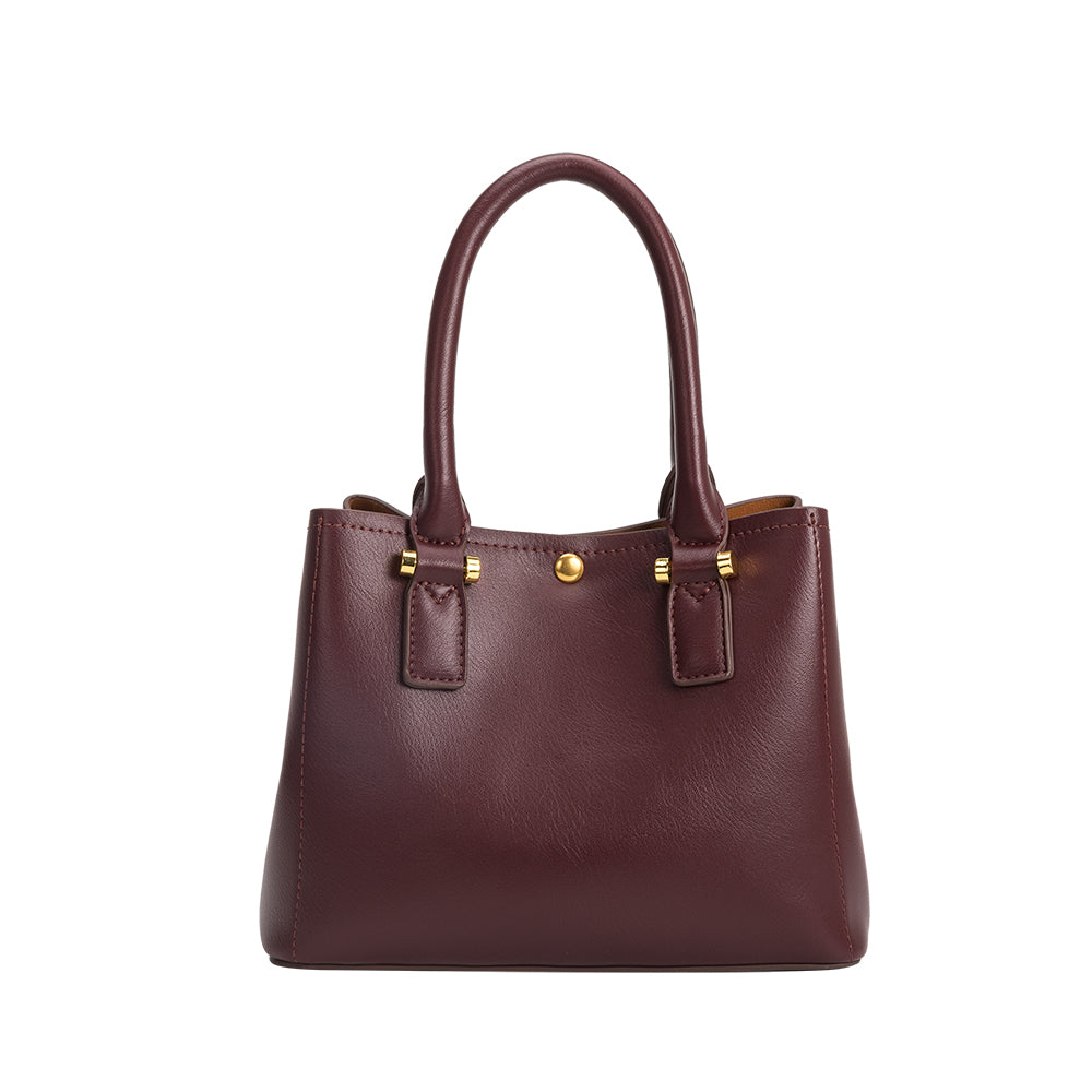 A small burgundy recycled vegan leather crossbody handbag with gold hardware. 