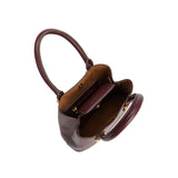 A small burgundy recycled vegan leather crossbody bag with gold hardware. 