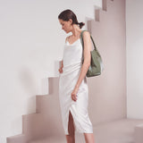 A model wearing a large vegan leather shoulder bag against a white wall. 