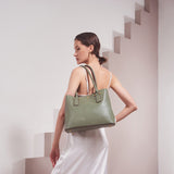 A model wearing a large vegan leather shoulder bag against a white wall. 