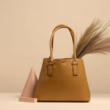 A still image of a large vegan leather shoulder bag with grass inside against a tan wall.