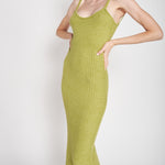 A model wearing a green midi dress against a white wall. 