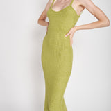 A model wearing a green midi dress against a white wall. 