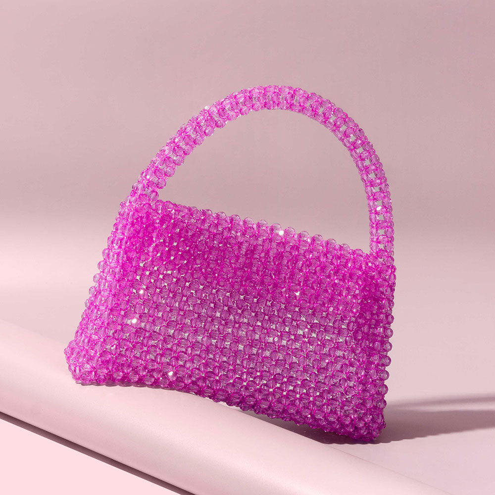 A still image of a crystal beaded top handle bag with a flap closure. 